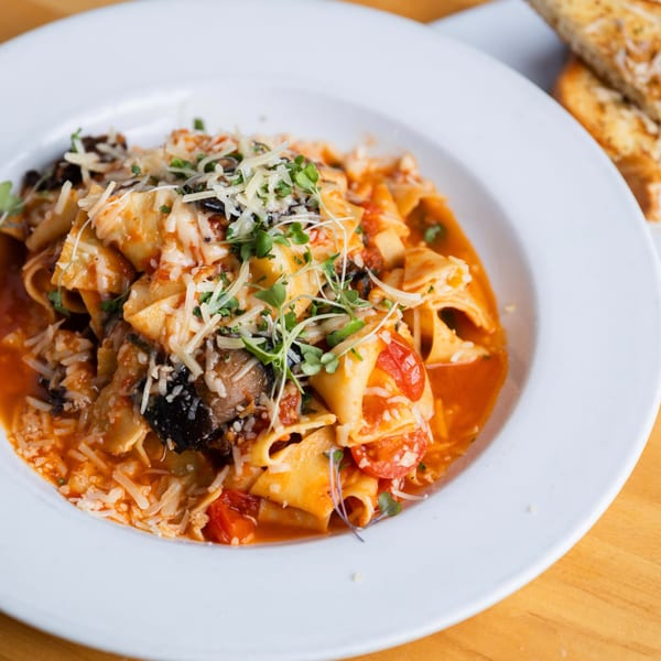 Fandee's Restaurant Sebastopol's pasta dish with red sauce, cheese, and microgreens, with toast in the background.