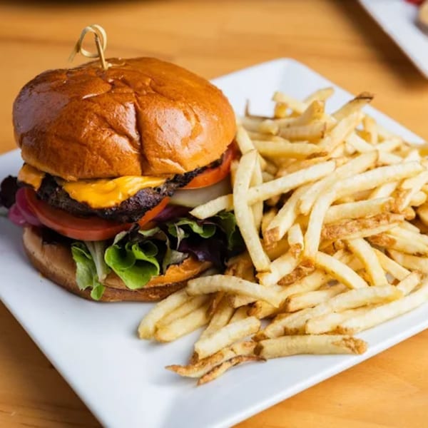 A Fandee's Restaurant cheeseburger with lettuce, tomato, and onion, served with golden french fries.
